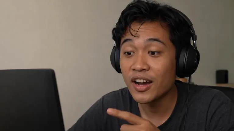 Pria berheadphone menunjuk layar dengan semangat