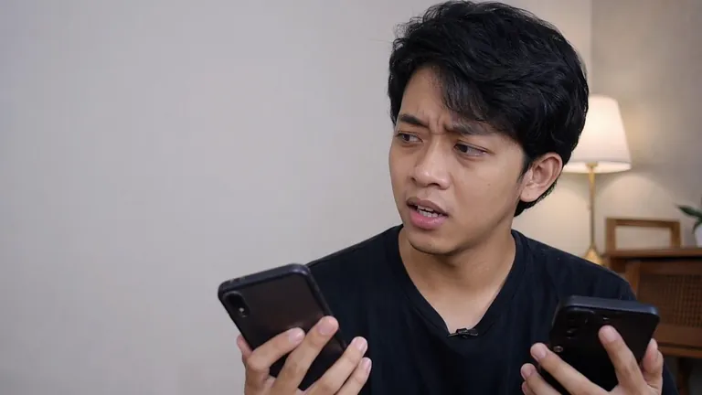 Pria bingung membandingkan dua HP
