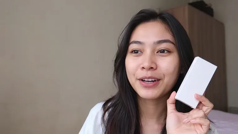 Perempuan tersenyum memegang kotak produk