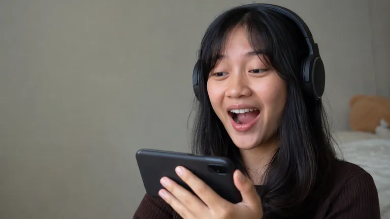 Perempuan berheadphone tertawa kaget melihat live
