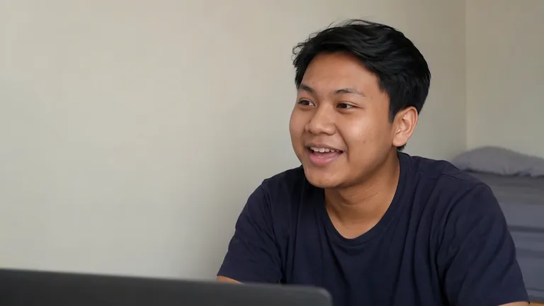 Pria menyeringai sambil mengetik di laptop