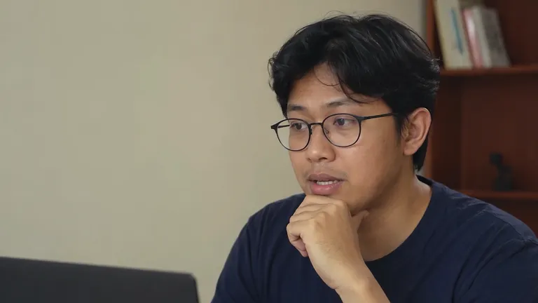 Pria berkacamata mengangguk di depan laptop
