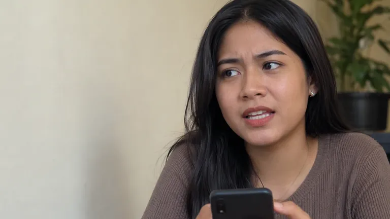 Perempuan waspada memegang HP di kafe