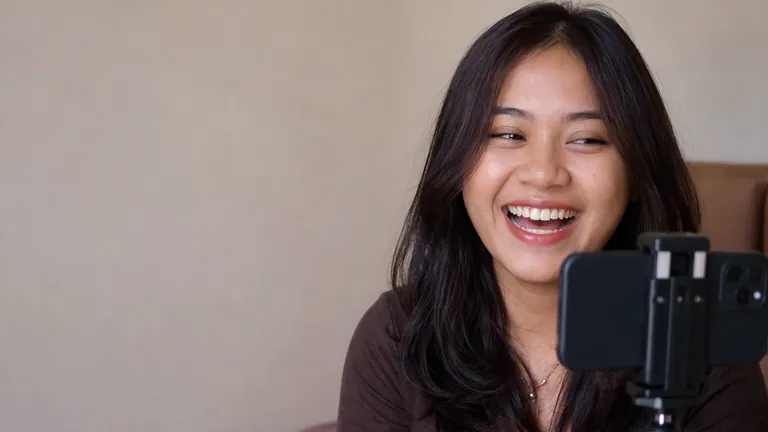 Perempuan tertawa merekam diri dengan HP