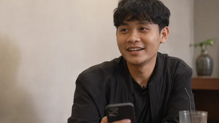 Pria menyeringai melihat HP di kafe