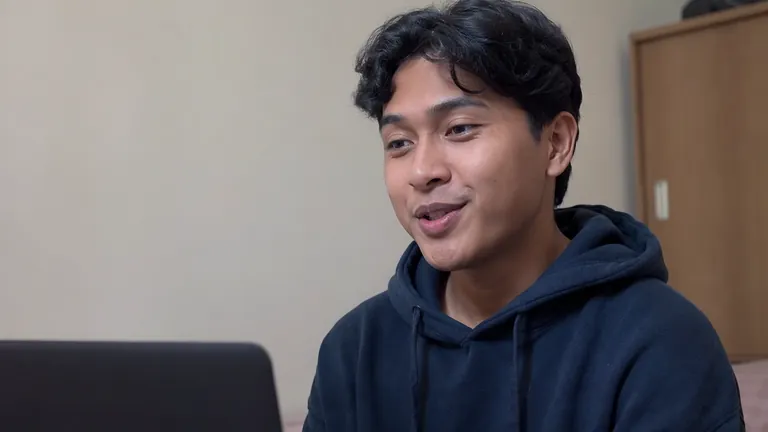 Pria berhoodie mengangguk puas di depan laptop