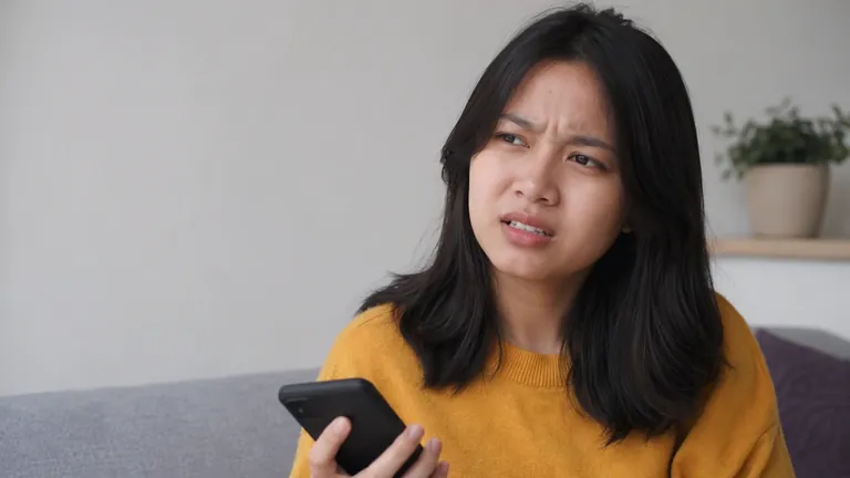 Perempuan menatap HP dengan bingung