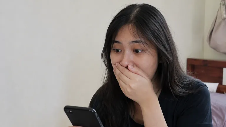 Perempuan terkejut menutup mulut melihat HP