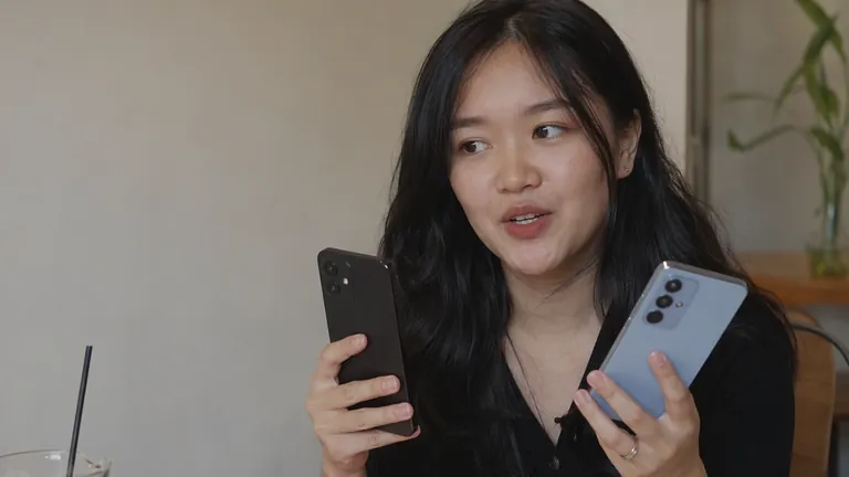 Perempuan membandingkan dua HP dengan serius