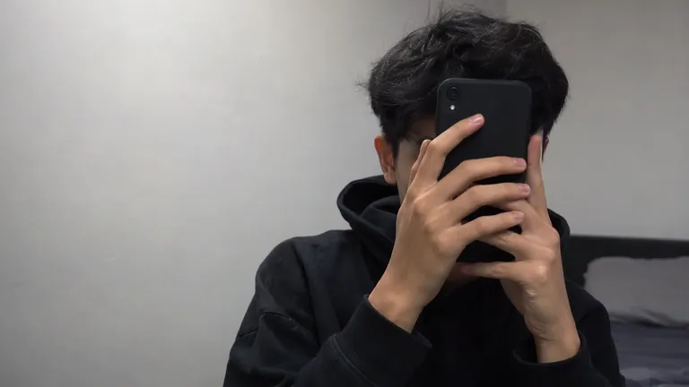 Orang berhoodie menutupi wajah dengan HP