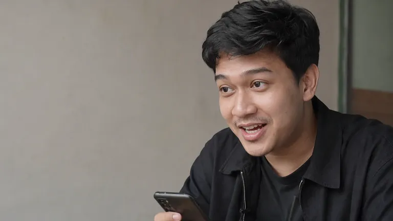 Pria menyeringai membaca HP di kafe