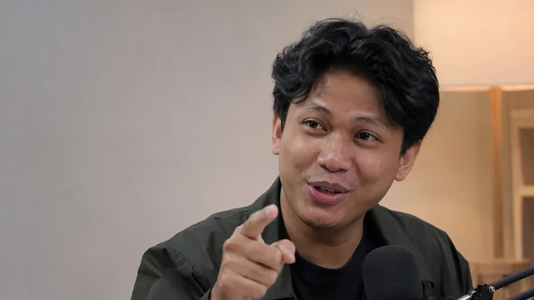Pria menunjuk kamera dengan senyum yakin