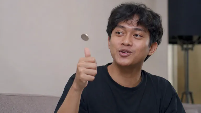 Pria tersenyum jahil melempar koin untuk memutuskan